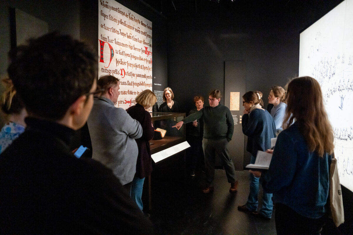 A group of people is gathered in the exhibition Upholding the Law: Upholding the law: Magnus the Lawmender’s National Law, 1274–2024