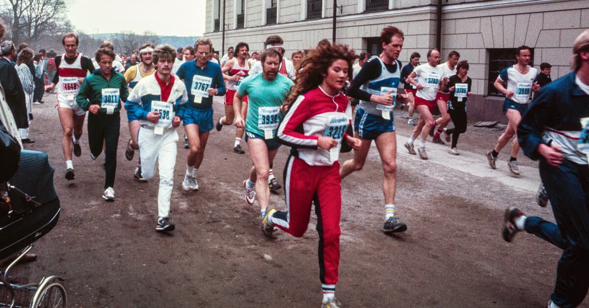 En gruppe mennesker i fargerikt trimtøy løper maraton forbi Slottet