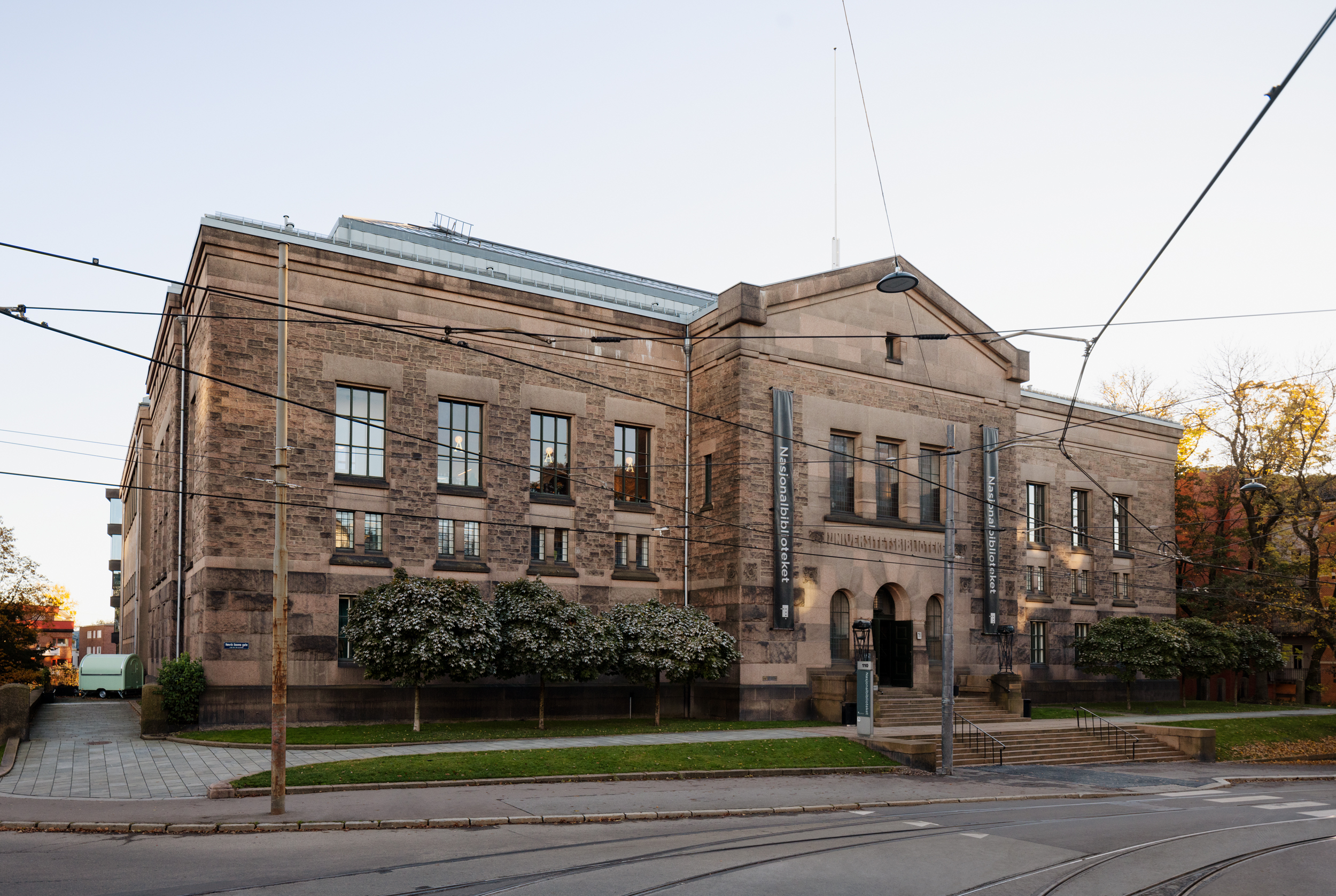 A large brown granite building. Trees in front. 